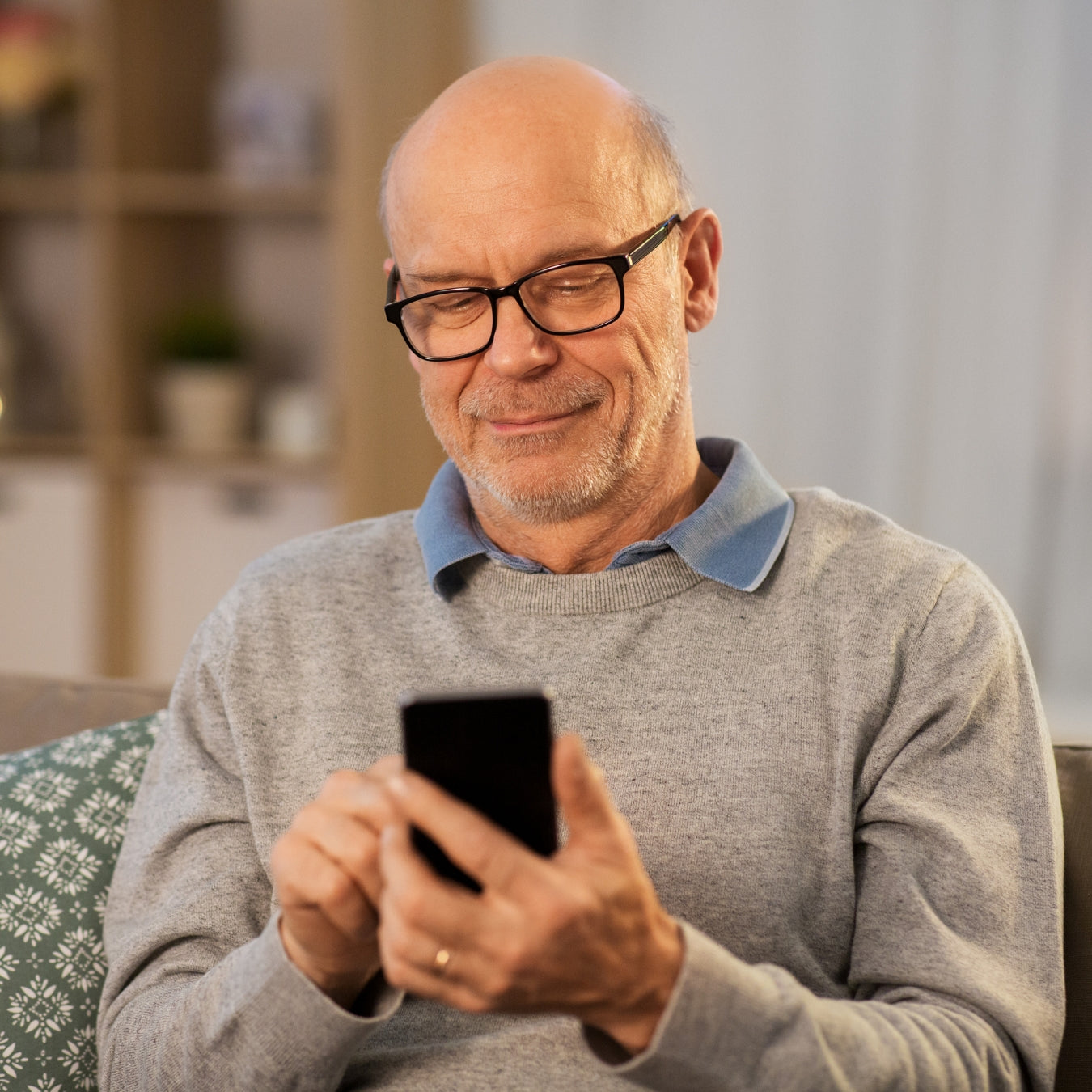 Happy senior man with glasses smiling while using mobile phone
