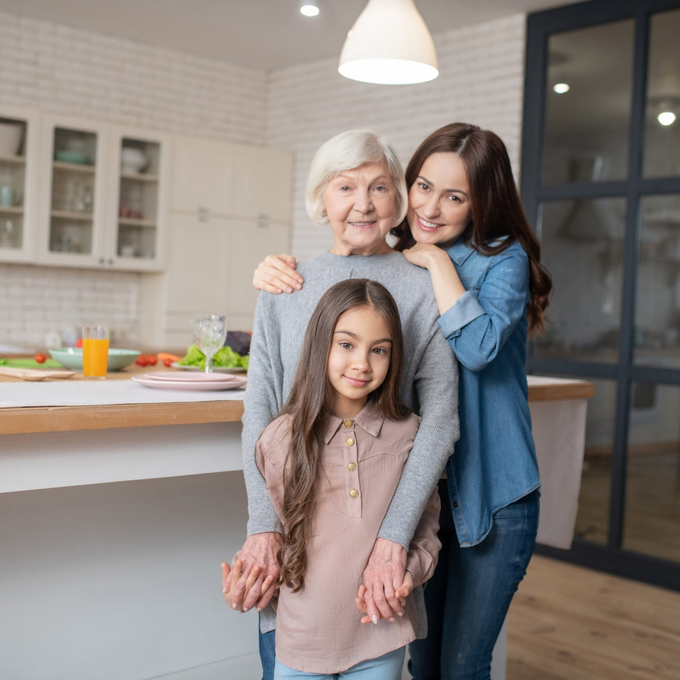 Happy multigenerational family smiling together in modern white kitchen